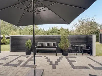 a patio with a bench and tables and an umbrella at Holiday Home Henriete - 3-5km from the sea by Interhome in Fjerritslev