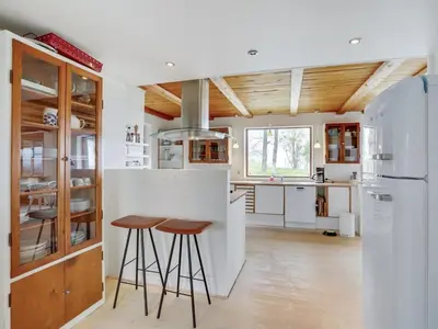 a kitchen with a bar with stools and a refrigerator at Holiday Home Nella - 1-2km from the sea by Interhome in Fjerritslev