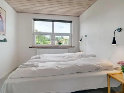 a white bedroom with a large bed with a window at Holiday Home Swipdagh - 600m from the sea by Interhome in Fjerritslev