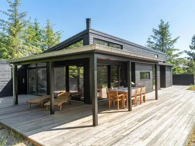 a house with a deck with a table and chairs at Holiday Home Gunnor - 1-3km from the sea by Interhome in Fjerritslev