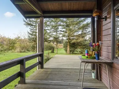 a wooden deck with a table and flowers on it at Holiday Home Artur - 1-5km from the sea by Interhome in Fjerritslev