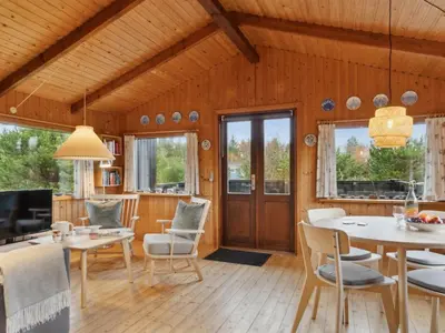 a living room with wooden walls and a dining room at Holiday Home Asmo - 350m from the sea by Interhome in Fjerritslev