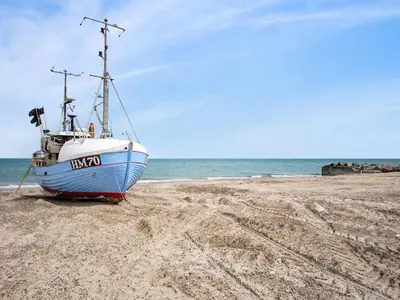 a boat sitting on the sand on a beach at Holiday Home Asmo - 350m from the sea by Interhome in Fjerritslev