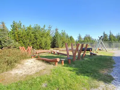a group of wooden benches sitting in the grass at Holiday Home Gunnie - 1-1km from the sea by Interhome in Fjerritslev