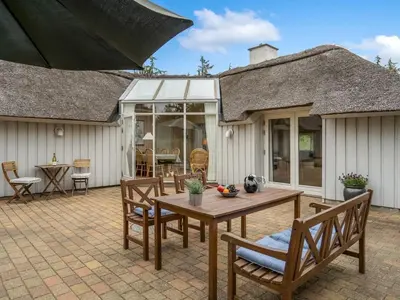 a patio with a wooden table and chairs at Holiday Home Gunnie - 1-1km from the sea by Interhome in Fjerritslev