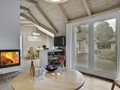a living room with a table and a fireplace at Holiday Home Catarine - 1-1km from the sea by Interhome in Fjerritslev