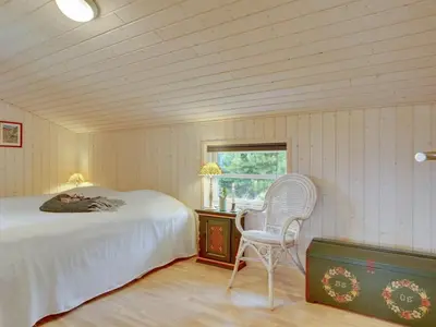 a bedroom with a bed and a chair and a window at Holiday Home Frida - 700m from the sea by Interhome in Fjerritslev