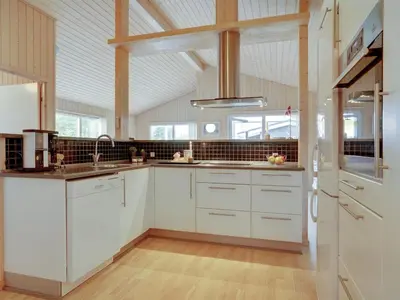 a large kitchen with white cabinets and a vaulted ceiling at Holiday Home Frida - 700m from the sea by Interhome in Fjerritslev