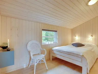 a bedroom with a bed and a chair in it at Holiday Home Frida - 700m from the sea by Interhome in Fjerritslev