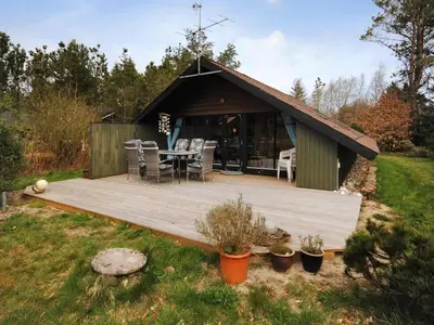 a wooden deck with a table in a garden at Holiday Home Deni - 4km from the sea by Interhome in Fjerritslev