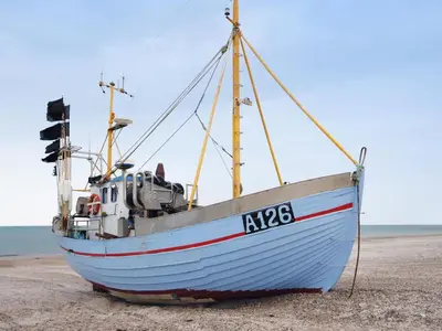 a blue boat sitting on the beach at Holiday Home Deni - 4km from the sea by Interhome in Fjerritslev