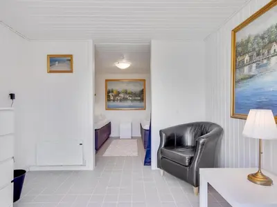 a living room with a leather chair and a bed at Holiday Home Bitta - 500m from the sea by Interhome in Fjerritslev