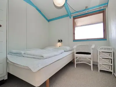 a bedroom with a bed with a chair and a window at Holiday Home Momme - 500m from the sea by Interhome in Fjerritslev