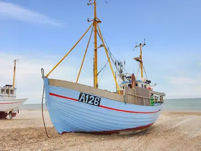 a blue boat sitting on the sand on a beach at Holiday Home Momme - 500m from the sea by Interhome in Fjerritslev