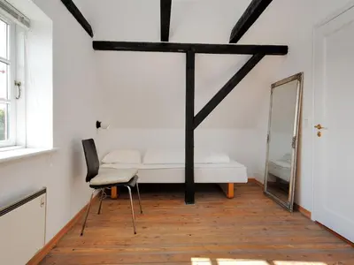 a room with a bed and a chair and a mirror at Holiday Home Indi - 400m from the sea by Interhome in Fjerritslev