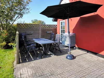 a table and chairs and an umbrella on a patio at Holiday Home Indi - 400m from the sea by Interhome in Fjerritslev