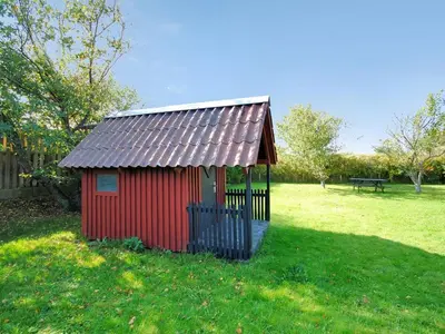 a small red shed in a field of grass at Holiday Home Indi - 400m from the sea by Interhome in Fjerritslev
