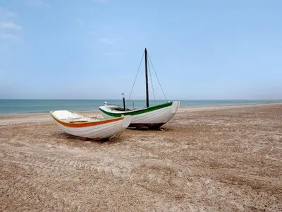 two boats are sitting on a sandy beach at Holiday Home Indi - 400m from the sea by Interhome in Fjerritslev