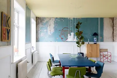 a dining room with a blue table and green chairs at 18b Ferielejlighed in Harboør