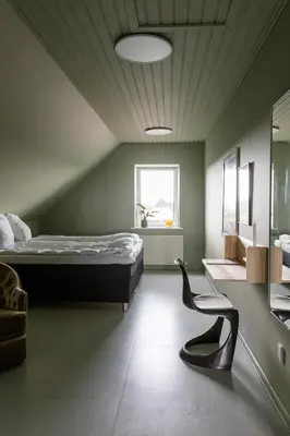 a bedroom with a bed and a chair in it at 18b Ferielejlighed in Harboør