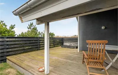 a wooden deck with a chair and an umbrella at Amazing Home In Thisted With Sauna in Torsted