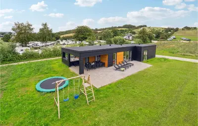 a black house with a playground in a yard at Awesome Home In Løgstrup With Kitchen in Løgstrup