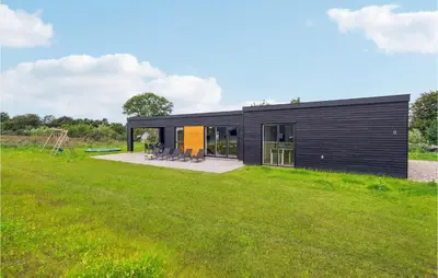 a black house with a large yard at Awesome Home In Løgstrup With Kitchen in Løgstrup
