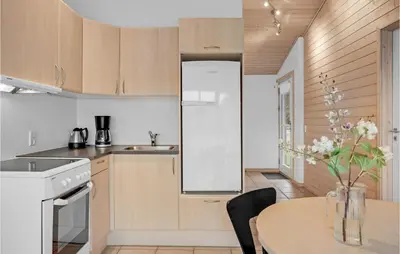 a kitchen with a table and a white refrigerator at Lovely Home In Pandrup With Kitchen in Pandrup