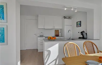 a kitchen with white cabinets and a table and a sink at 2 Bedroom Gorgeous Apartment In Blokhus in Blokhus