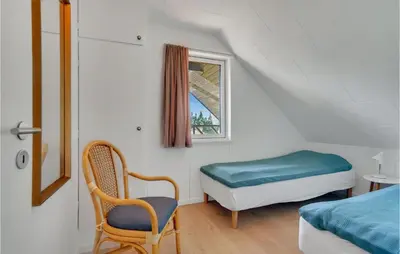 a bedroom with a bed and a chair and a window at 2 Bedroom Gorgeous Apartment In Blokhus in Blokhus