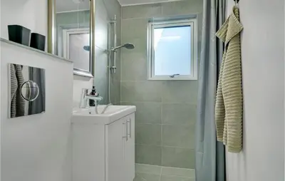 a white bathroom with a sink and a shower at 2 Bedroom Gorgeous Apartment In Blokhus in Blokhus