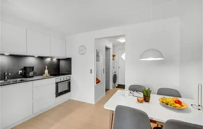 a kitchen with white cabinets and a table and chairs at Cozy Home In Lemvig With Wifi in Lemvig