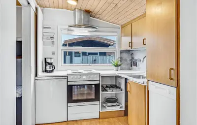 a kitchen with white appliances and wooden cabinets at Lovely Home In Hanstholm With Kitchen in Hanstholm