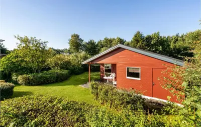 a red shed with a dog sitting in a yard at Amazing Home In Nykøbing M in Hesselbjerg