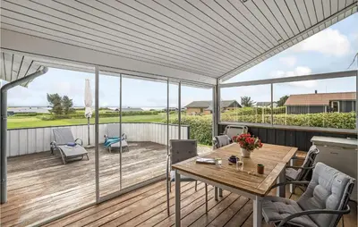a covered patio with a wooden table and chairs at Beautiful Home In Vinderup With Sauna in Vinderup