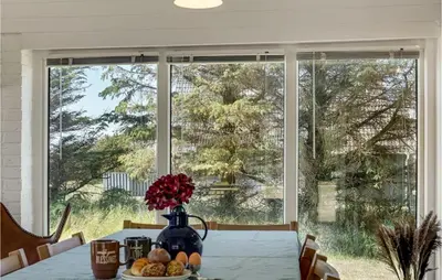 a dining room table with a vase of flowers and a large window at Awesome Home In Thisted With Kitchen in Thisted