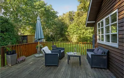 a deck with chairs and an umbrella and a table at Amazing Home In Thyholm With Wifi in Thyholm