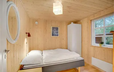 a bed in a room with a wooden wall at Amazing Home In Thyholm With Wifi in Thyholm