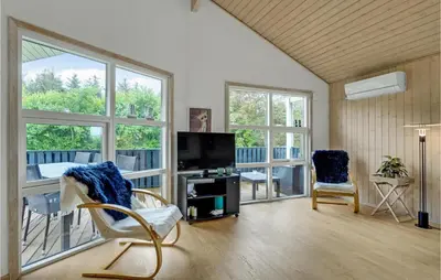 a living room with a tv and chairs and windows at Cozy Home In Hurup Thy With Sauna in Sønder Ydby