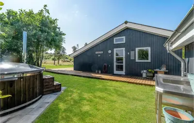 a backyard with a black building and a grill at Cozy Home In Hurup Thy With Sauna in Sønder Ydby