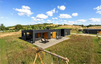 a black house on top of a grassy field at Pet Friendly Home In Løgstrup With Wifi in Løgstrup