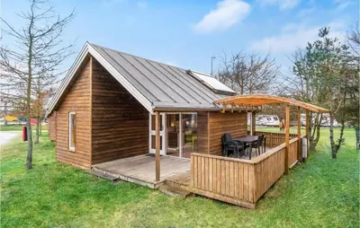 a wooden cabin with a deck with a table at Nice Home In Hanstholm With Kitchen in Hanstholm