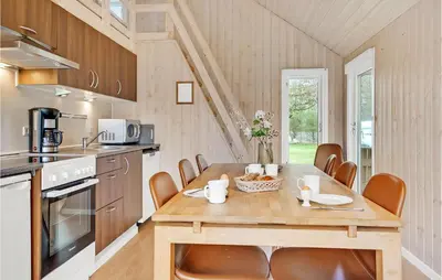 a kitchen with a wooden table and chairs in a room at Nice Home In Hanstholm With Kitchen in Hanstholm