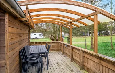 a wooden patio with a table and chairs on a wooden deck at Nice Home In Hanstholm With Kitchen in Hanstholm