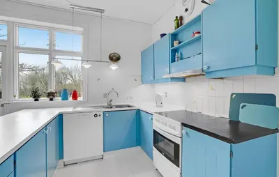 a blue kitchen with white appliances and blue cabinets at 6 Bedroom Amazing Home In Roslev in Roslev