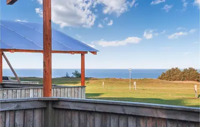 a view of a field with the ocean in the background at 2 Bedroom Nice Home In Hanstholm in Hanstholm