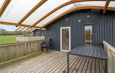 a large deck with a black house with a roof at 2 Bedroom Nice Home In Hanstholm in Hanstholm