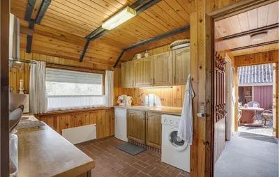 a kitchen with wooden cabinets and a washer and dryer at 4 Bedroom Pet Friendly Home In Løgstør in Løgstør