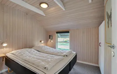two beds in a room with wooden walls and a window at Lovely Home In Vestervig With Wifi in Vestervig