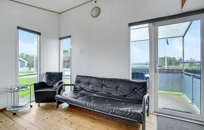 a black leather couch in a room with windows at Gorgeous Home In Vestervig With Kitchen in Vestervig